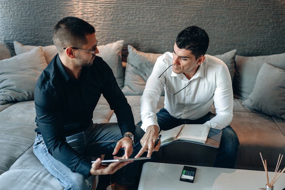 Two men collaborating on a business project using a tablet in an office setting.