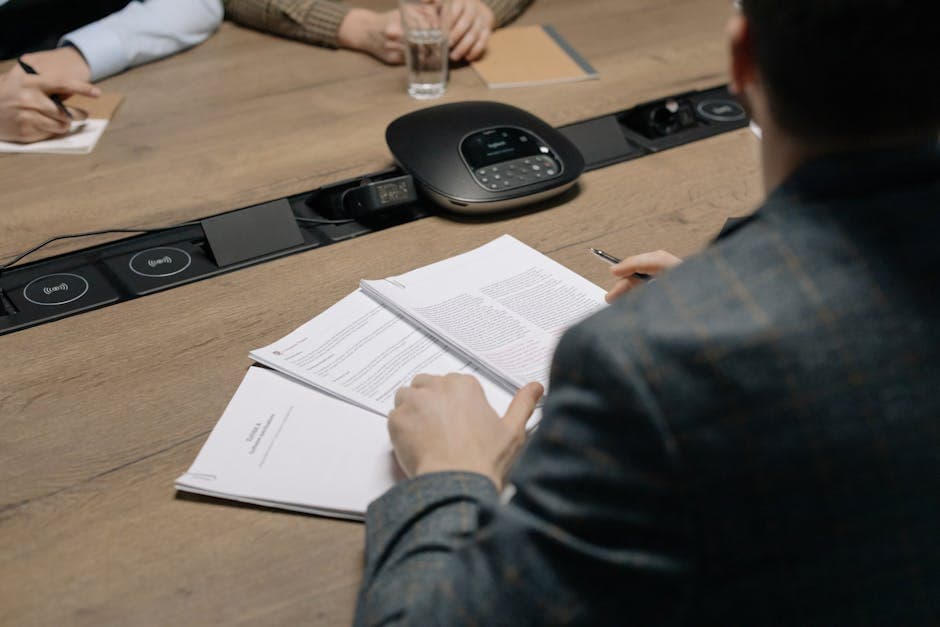 Close-up of business professionals reviewing documents during a meeting in a modern office setting.