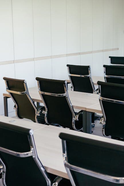 Empty modern conference room with sleek black chairs and wooden desks, perfect for business meetings.