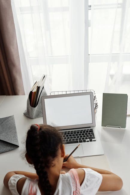 A young girl focuses on distance learning with her laptop at home.