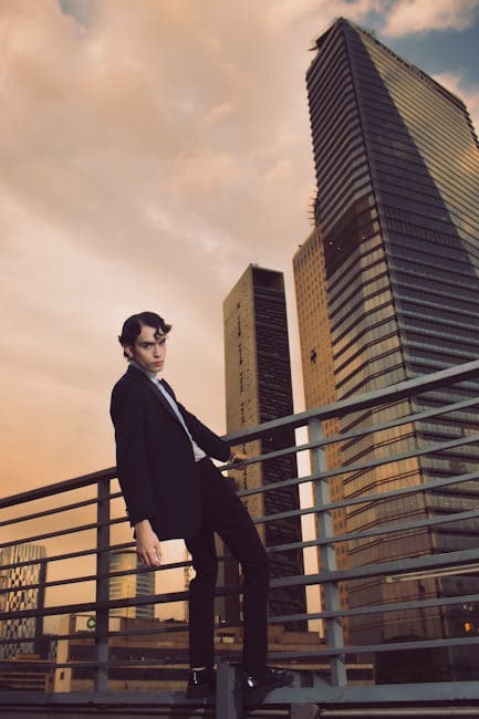 Man in suit standing on urban rooftop with city skyline at sunset.