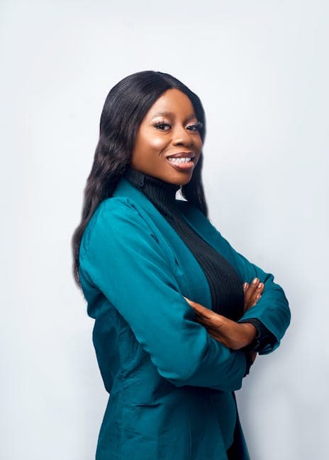 Businesswoman smiling in blue suit with arms crossed against white background.
