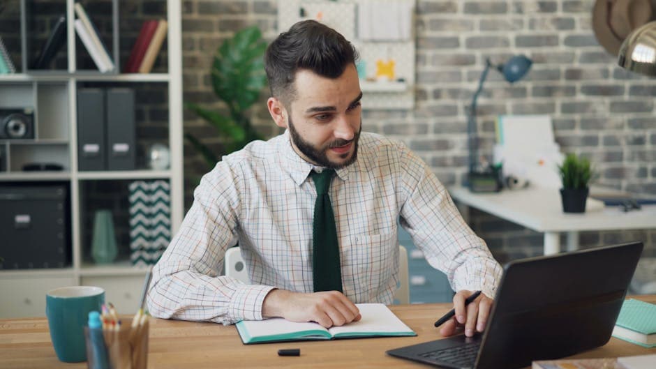 Confident young adult working on a laptop in a stylish modern office setting.