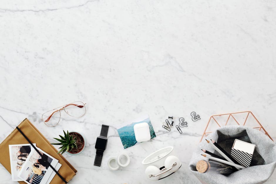 Flat lay of a marble desk featuring tech gadgets, stationery, and decor items, perfect for creatives.