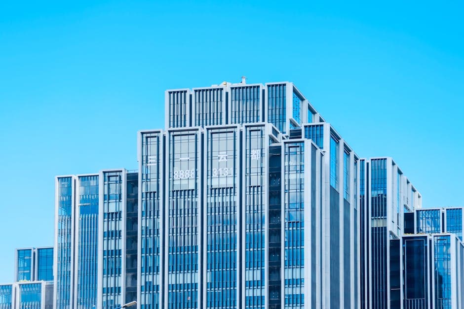 Contemporary glass building under bright daylight with clear blue sky backdrop.