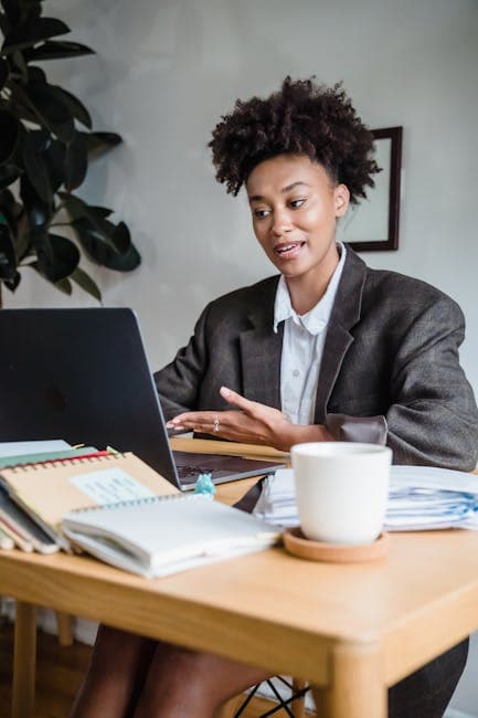 Professional woman on a video call, working remotely from home office with a laptop.