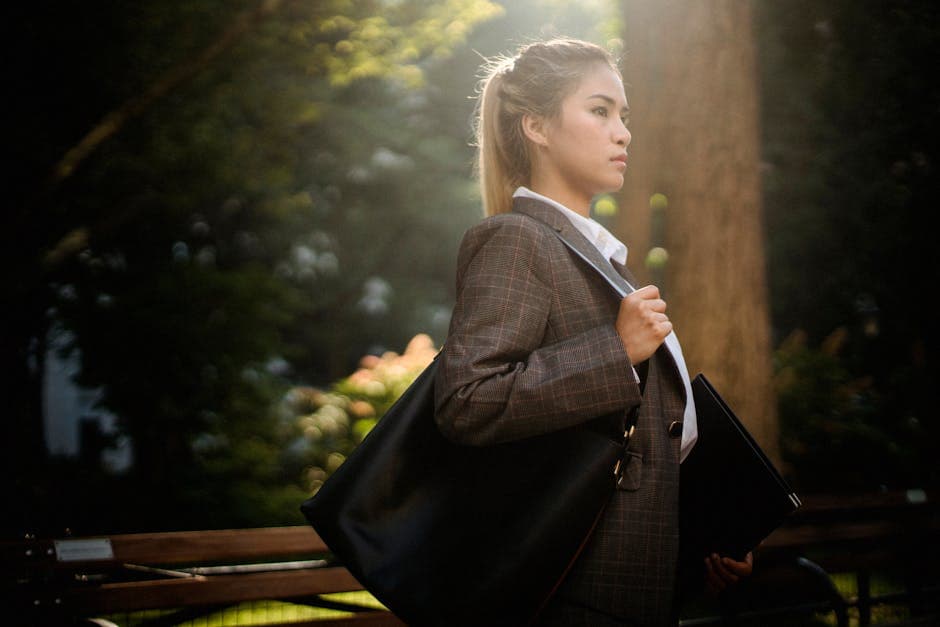 Young woman in suit walking confidently through a sunlit park.