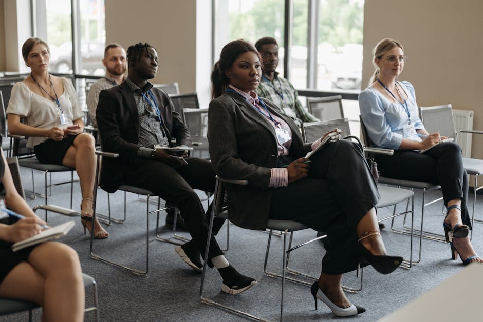 A diverse group of adults attentively listening at a business conference indoors.