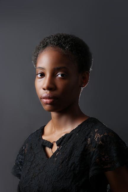 A striking studio portrait of a young woman in a black lace blouse, showcasing elegance and strength.