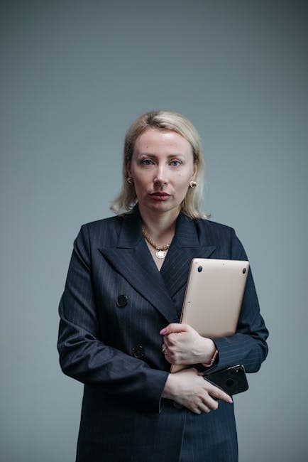 Professional businesswoman in a black blazer holding a laptop, showcasing confidence and leadership.