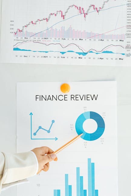 Close-up of financial analysis showing graphs, charts, and person pointing with pencil.