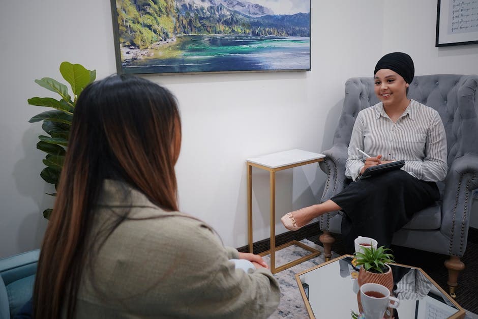 Two women in a cozy office setting engage in a friendly and casual meeting.